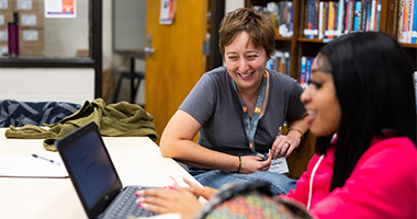 Female mentor works with her student in a library.