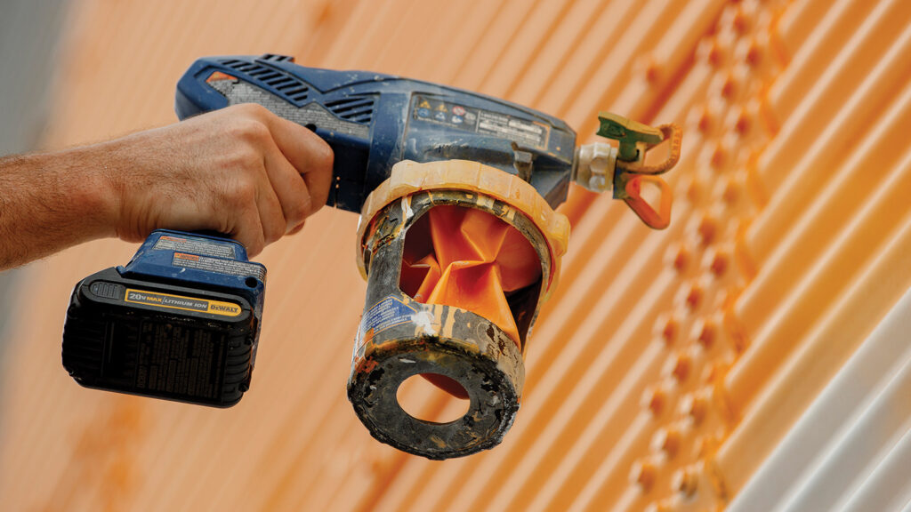 Close up of hand holding a paint gun to paint a mural.