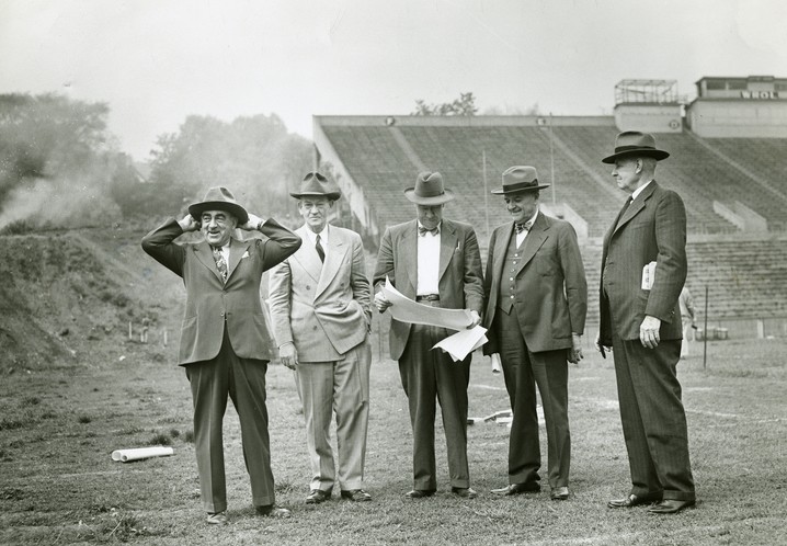 An old photo of a group of men looking at architectural plans.