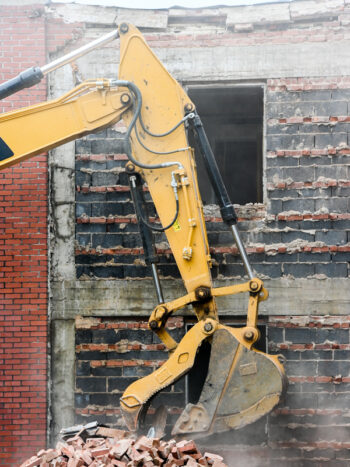 Image showing a construction vehicle picking up bricks during a demolition.