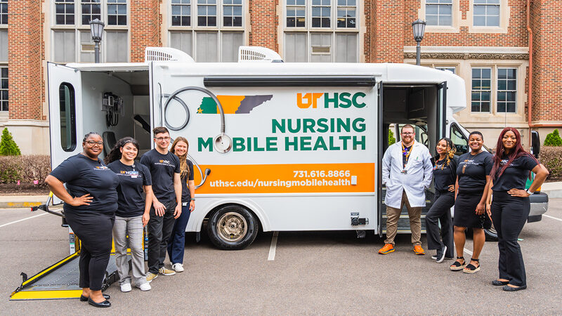 UTHSC students smiling while standing in front of the UTHSC Nursing Mobile Health vehicle.