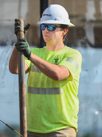 A construction worker holding a metal pole.