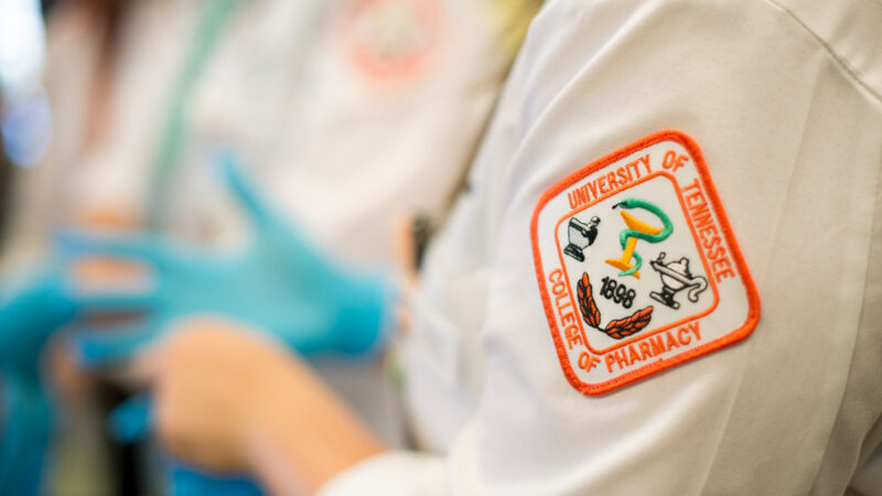 Close-up of a UT College of Pharmacy patch on the sleeve of a white medical coat.
