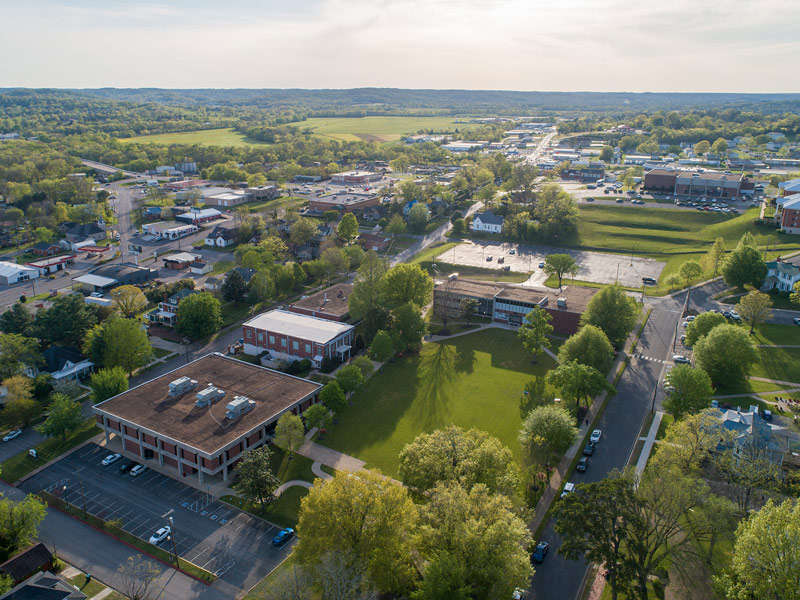 Aerial sunset photo of campus buildings and green lawns.