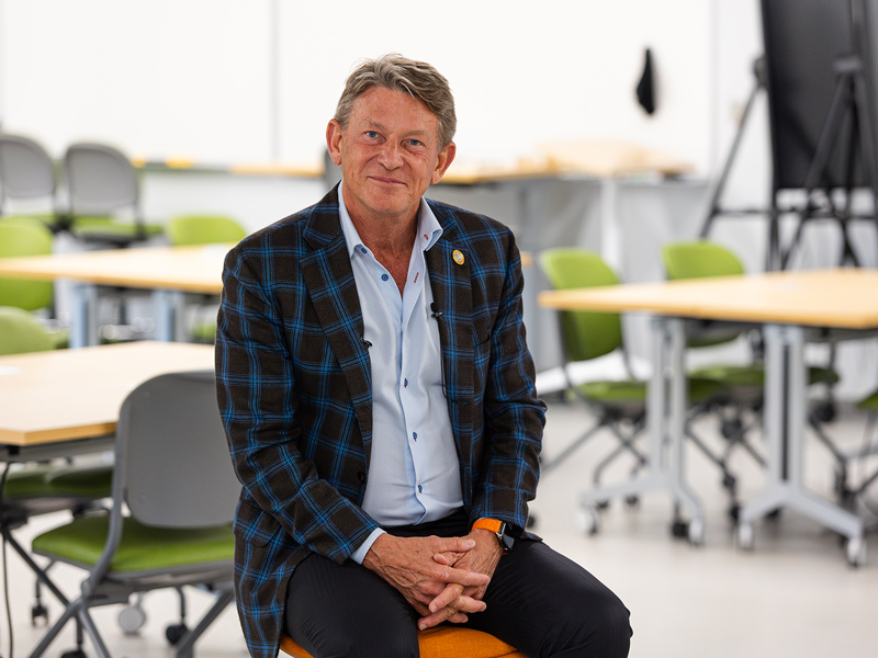Randy Boyd, wearing a plaid jacket, sits in a classroom for an interview.