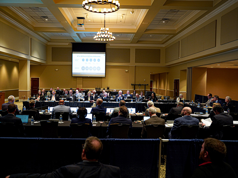 A large group of people conducting a meeting in a large conference room.
