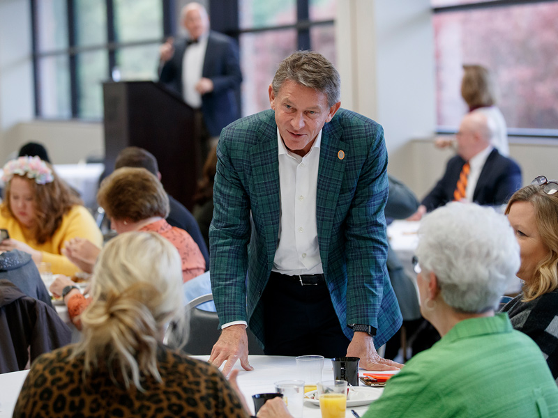 UT President Randy Boyd speaking with several women at a table during an event.