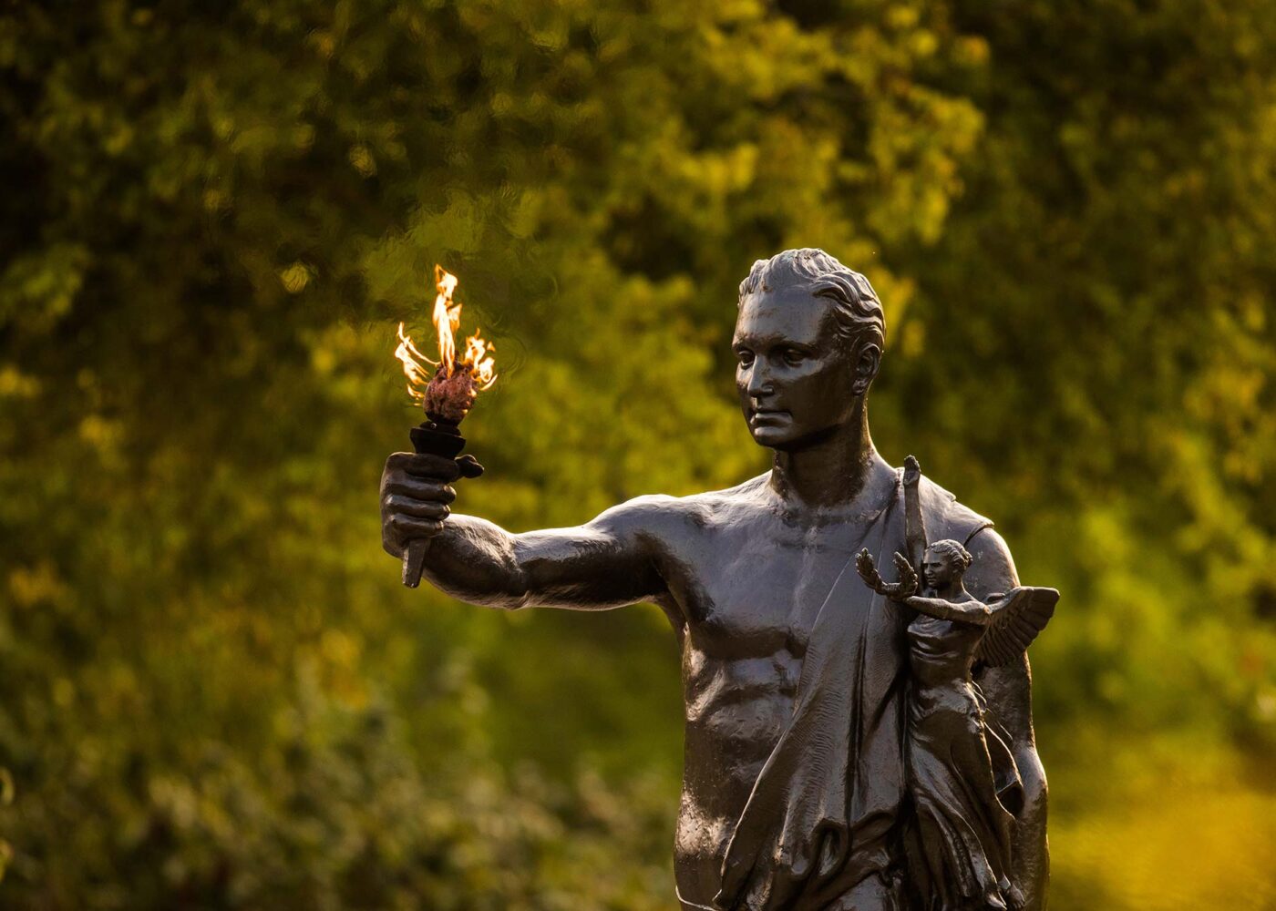 Large bronze statue holding of a person holding out a flaming torch.