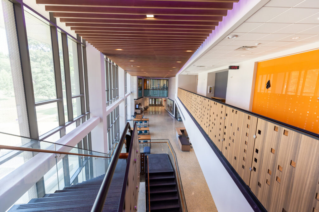 View looking down from stair landing into vast academic building corridor.
