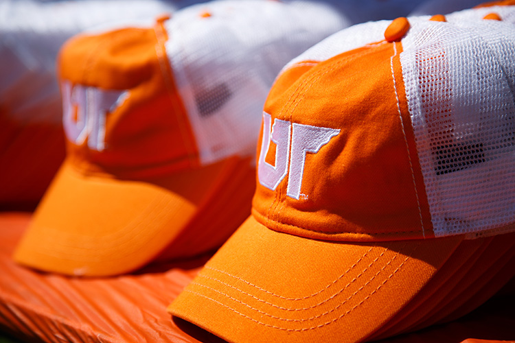 Orange and white baseball hats lined up on table