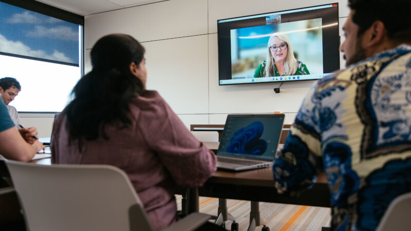 A group of employees participate in a video conference meeting.