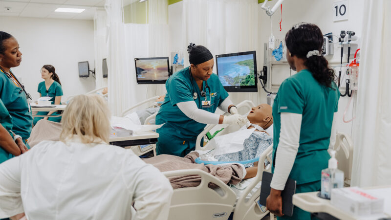 UTHSC nursing students practicing on a faux person with instructor.