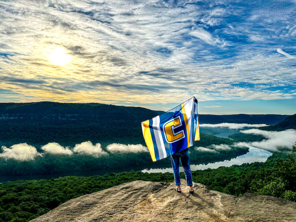 UTC student holding flag overlooking river