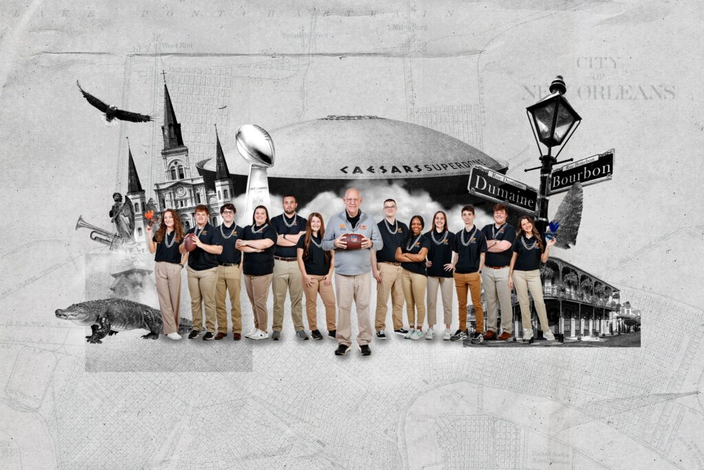 UT Martin students and faculty pose in front of a stylized backdrop featuring iconic New Orleans imagery, including the Caesars Superdome, French Quarter signs, and a large Lombardi Trophy, celebrating their experiential learning trip to the Super Bowl.