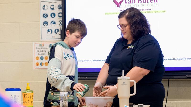 UT Extension employee helping a male student with a class demonstration at a Van Buren county school.