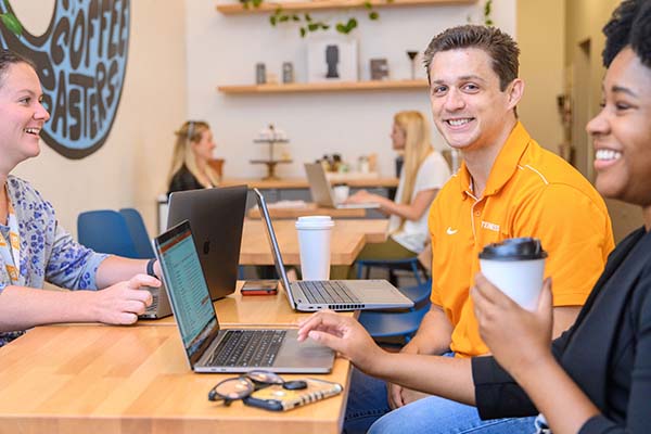 A group of UT employees chat and work while visiting a coffee shop.
