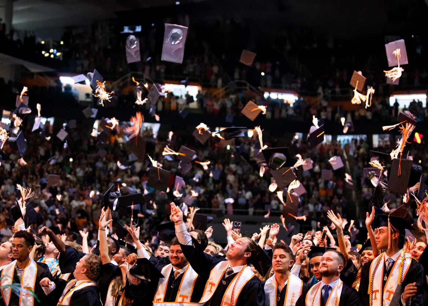 A group of graduating students throw their graduation caps in celebration.