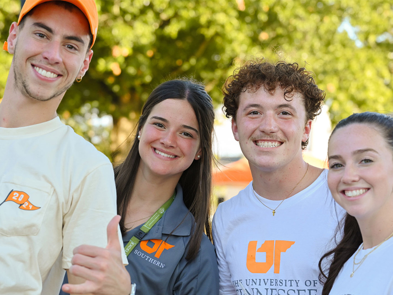Four smiling UT Southern students pose outdoors in UT-branded shirts.