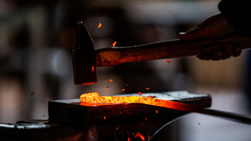 A blacksmith hammering on a red-hot piece of metal.