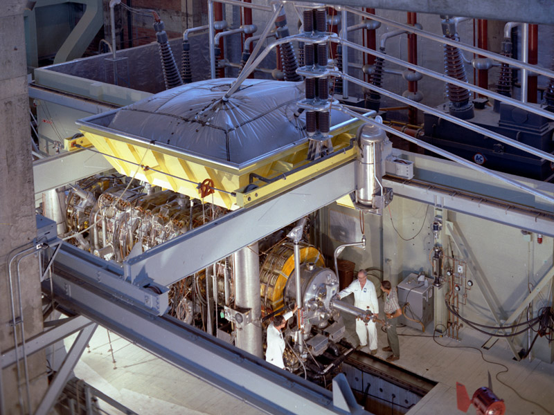 Three scientists working on a large piece of research equipment.