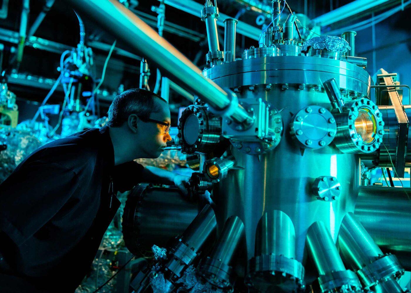 A young scientists examines a chamber of a complicated piece of machinery.