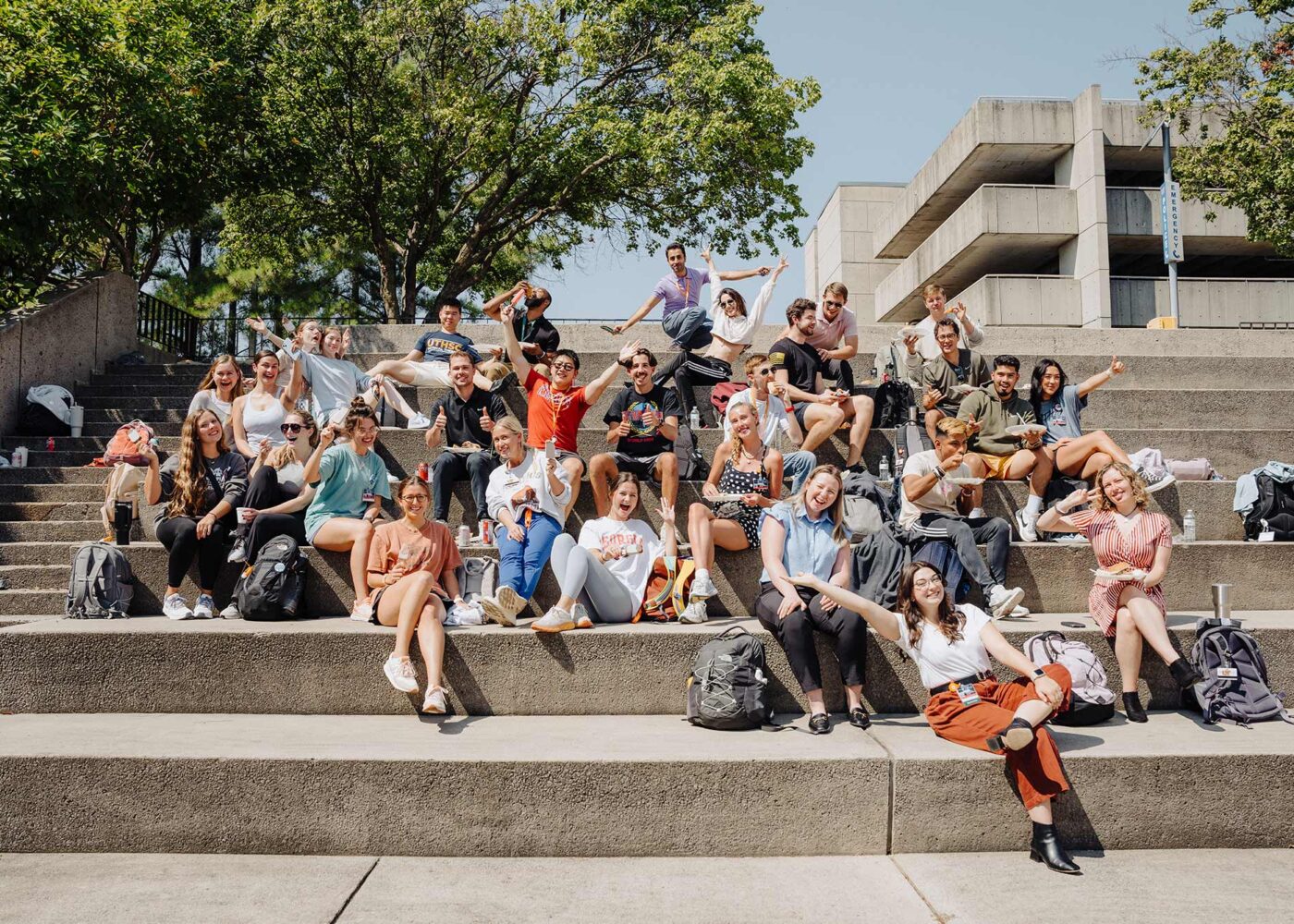 A group of students sit together in an outdoor amphitheater.