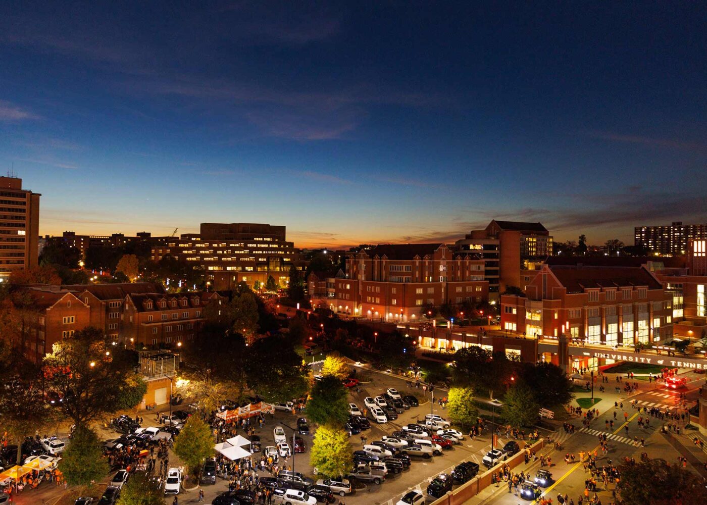 Night time aerial photo of UT Knoxville, lit up by street lights and the fading sunlight in the horizon.