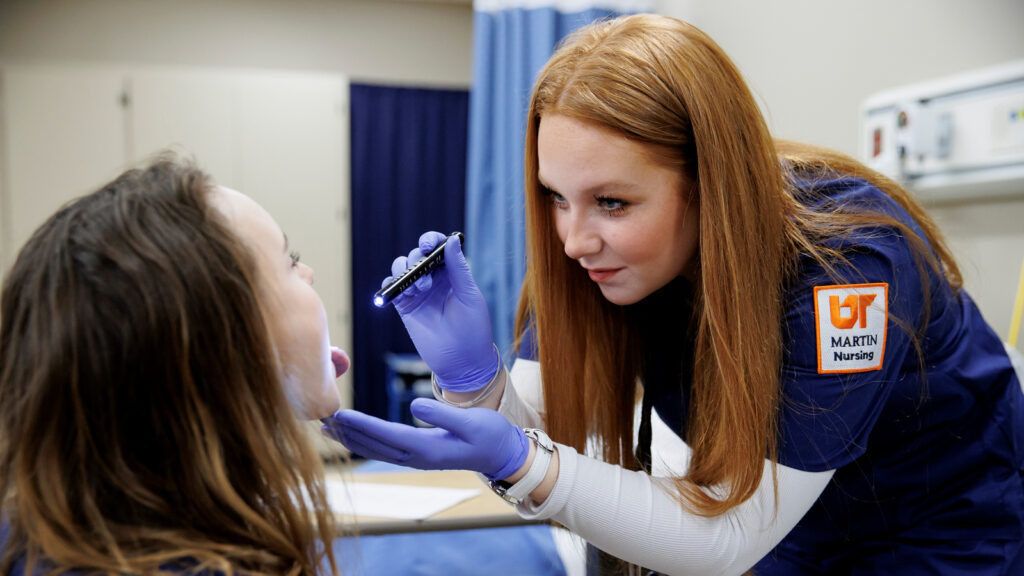 UTM Nursing student examining a patient.