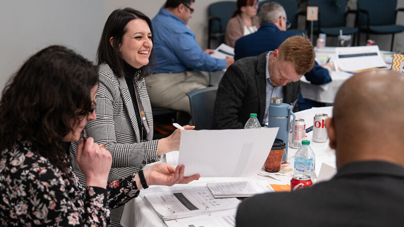 Women and men sitting at a table while attending the Center for Industrial Services (CIS)'s technical assistance and training.