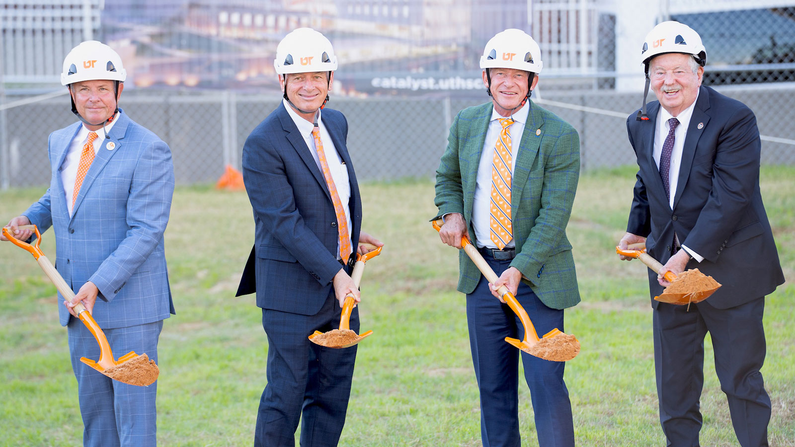Four business men holding shovels of dirt at a groundbreaking ceremony.