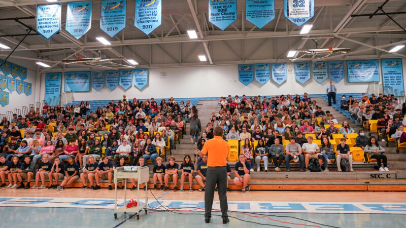 Randy Boyd speaking to a group of high school students inside of a gym during a tour.