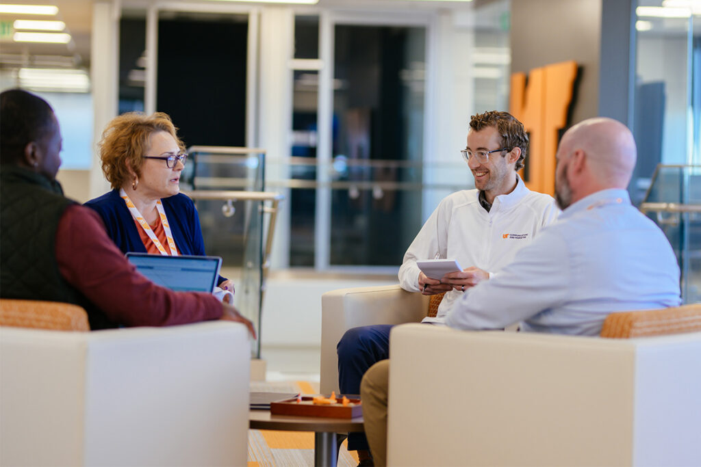 A group of people sitting in a circle, smiling and having a discussion.