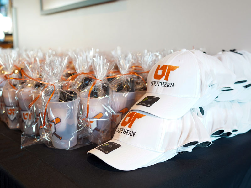 UT Southern branded baseball caps and promotional items featuring the university logo and school colors, produced through a university vendor partnership.