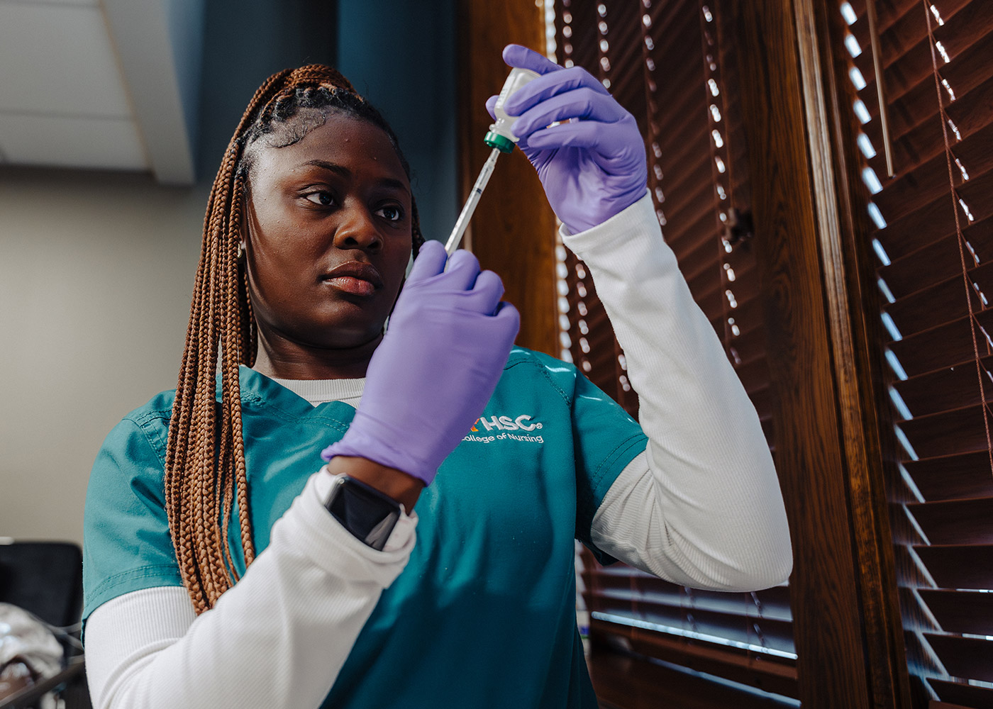 A nursing student filling a syringe from a vial.