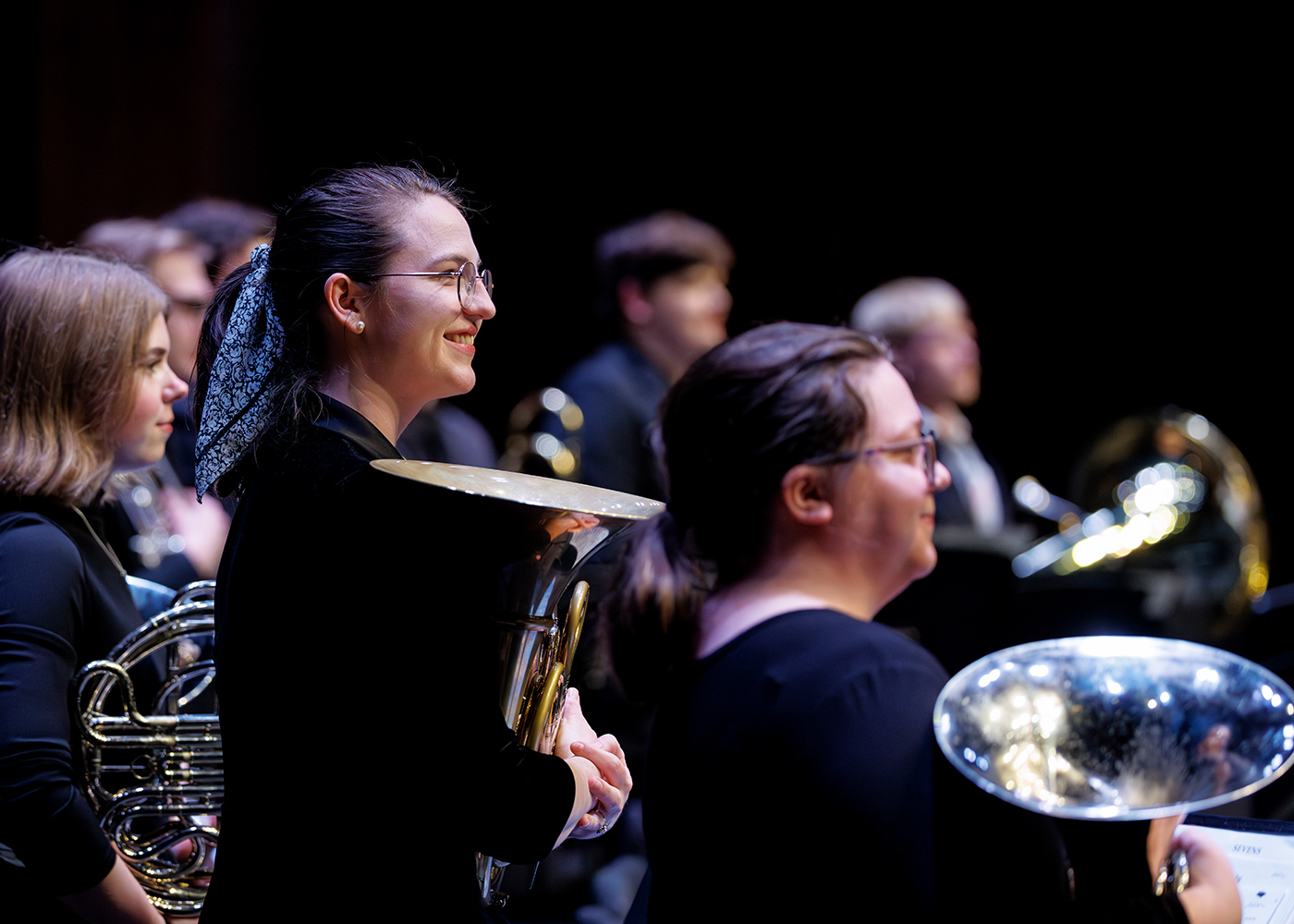 A group of wind ensemble students with their instruments awaiting instructions from the conductor.