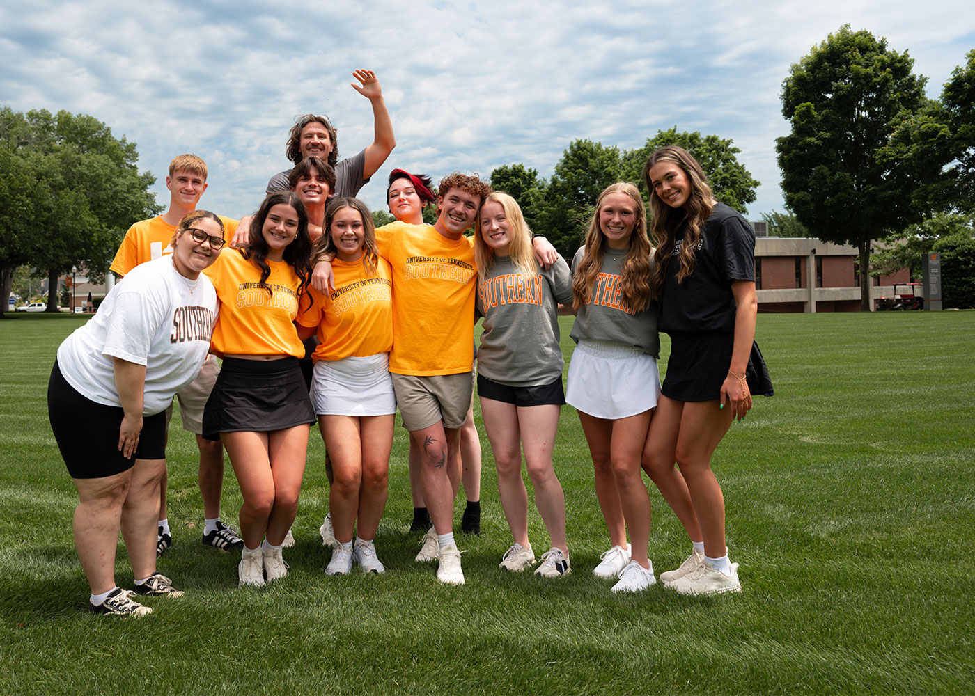 A group of students smiling for a photo on a grass field.