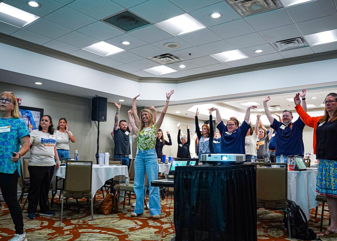 A group of people standing and waving their arms for a group activity.