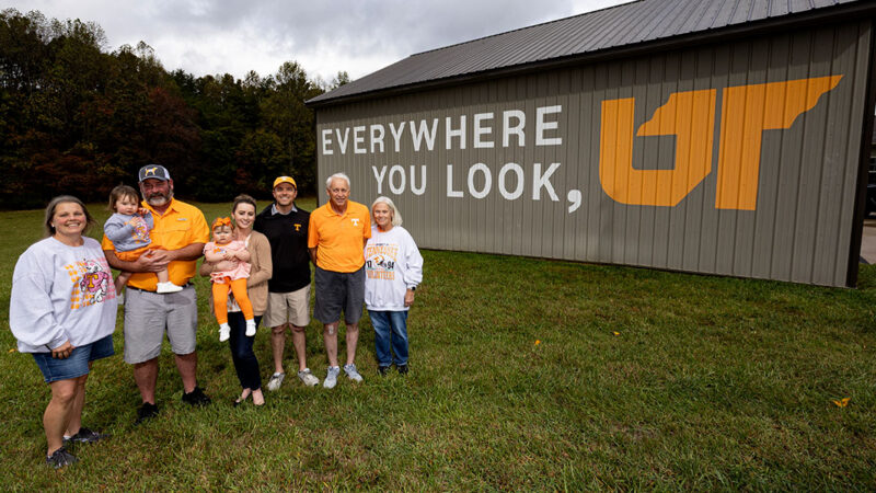 Group of people standing in front of a bard that has the Everywhere You Look, UT campaign logo on it.