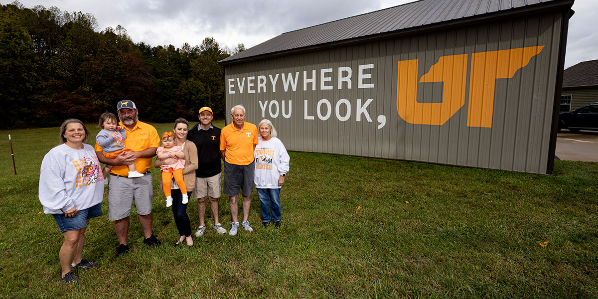 Group of people standing in front of a bard that has the Everywhere You Look, UT campaign logo on it.